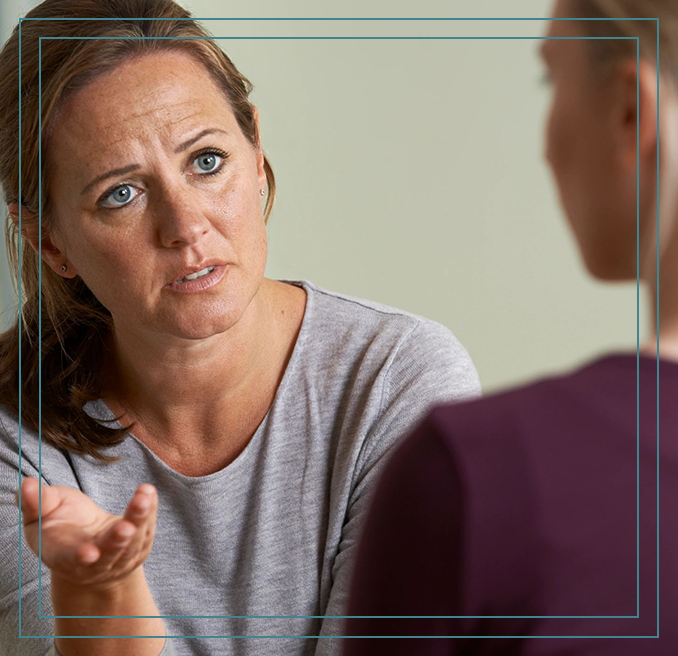 A woman is talking to another person in front of a mirror.