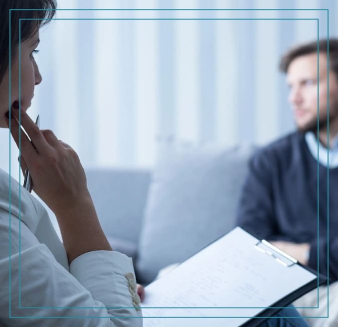 A woman talking on the phone while sitting in front of another man.