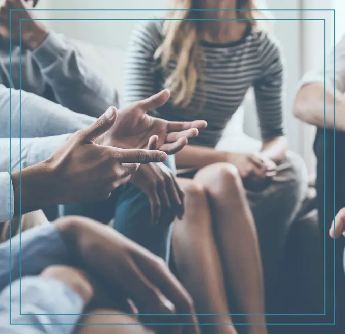 A group of people sitting around talking to each other.