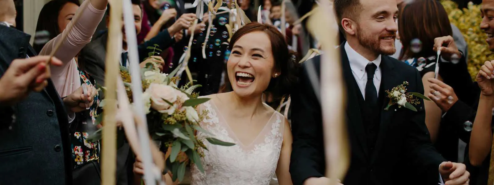 A bride laughing while holding her bouquet.